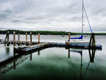 Pier on lake against cloudy sky