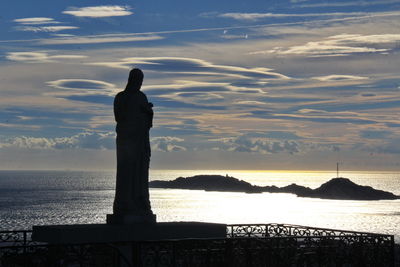 Silhouette christ statue over mediterranean sea and  les iles against sky during sunset