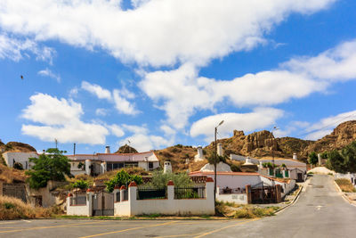 Houses by road amidst buildings against sky