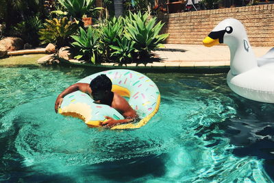 Shirtless man with inflatable ring in swimming pool