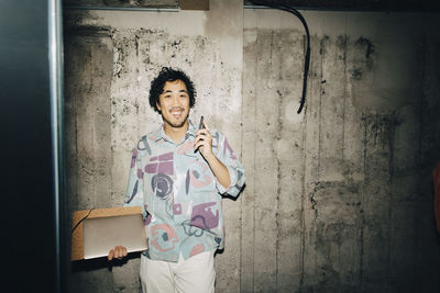 Portrait of a smiling young man standing against wall