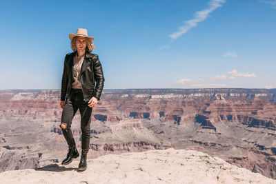 Man wearing hat standing on mountain against sky