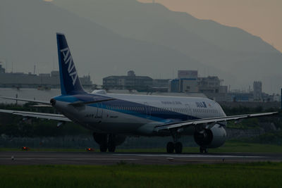 Airplane on airport runway against sky