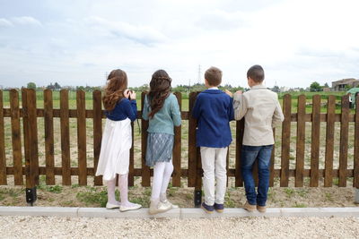 Rear view of children standing against sky