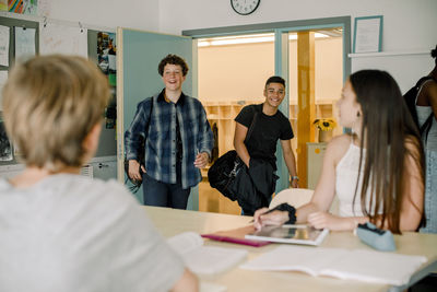 Smiling male students entering in classroom