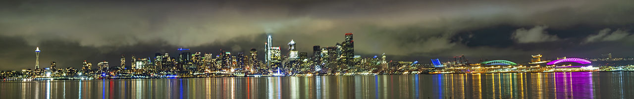 Illuminated modern buildings in city against sky at night