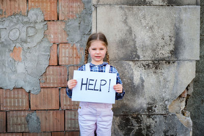 Portrait of girl holding poster against wall