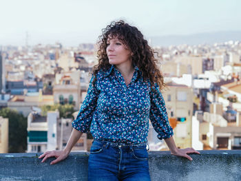 Beautiful young woman standing against cityscape