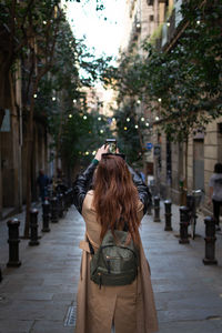 Rear view of woman standing on footpath in city