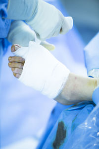 Cropped image of surgeon wrapping bandage on patient wounded foot