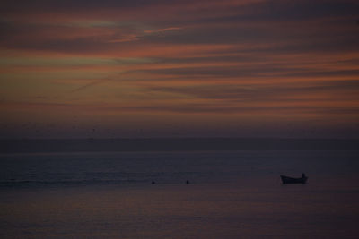 Silhouette boat in calm sea at sunset
