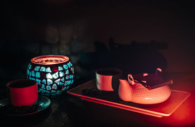 Tea set on dark background illuminated with dim light whit a candle