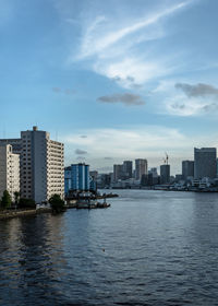 Sea by buildings against sky in city