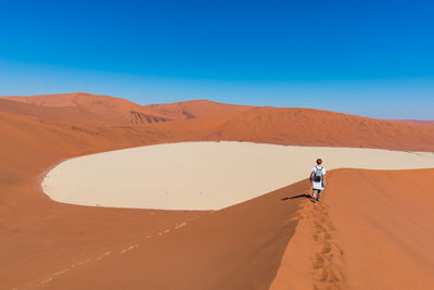 Man standing in desert against clear blue sky