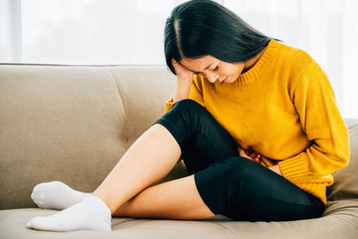 Young woman sitting on sofa at home