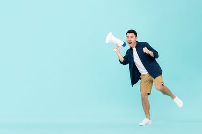 Full length of a smiling young man against blue background