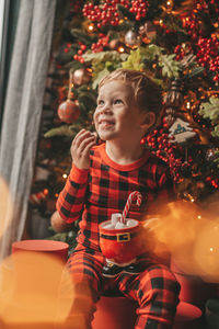 Portrait of young woman standing against christmas tree