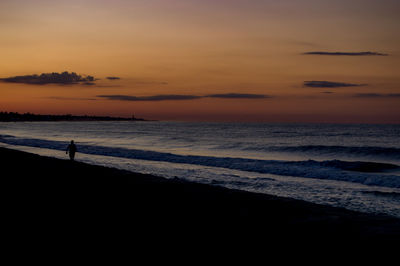 Silhouette people on beach against sky during sunset