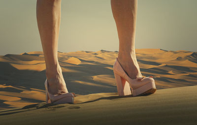 Low section of woman standing on sand at beach