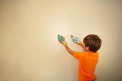 Rear view of woman holding gift against wall