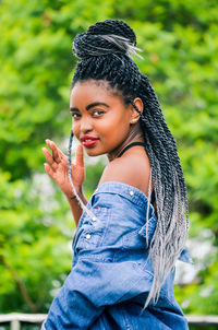 Portrait of beautiful woman with long dreadlocks standing at park