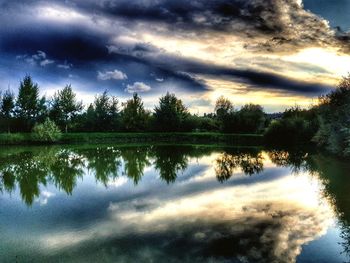 Reflection of silhouette trees in lake against sky