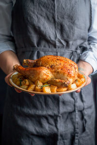 Midsection of woman holding meat with potatoes in plate