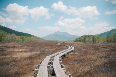 Scenic view of road by mountains against sky