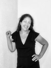 Portrait of smiling young woman standing against wall