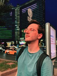 Portrait of young man standing against buildings