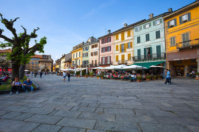 People on footpath by buildings in city