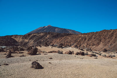 Scenic view of arid landscape against clear blue sky