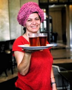 Portrait of smiling woman holding plate with drinks