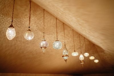 From below of various bright glowing lanterns in traditional moroccan style hanging under ceiling in room