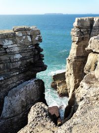 Scenic view of sea by cliff against sky