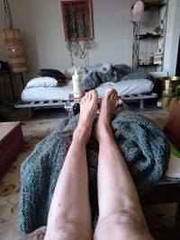 Low section of woman relaxing on bed at home