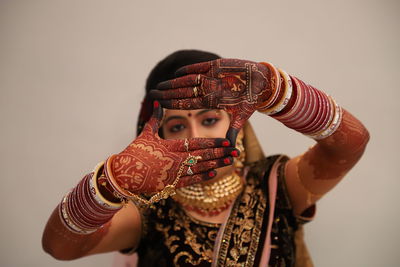 Close-up portrait of bride gesturing against beige background