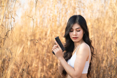 Young woman using phone while standing on field