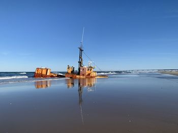 Sailboat on beach against blue sky