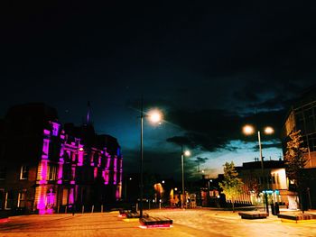 Empty road along illuminated street lights at night