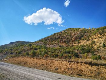 Scenic view of road by mountains against blue sky