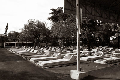 Empty benches in cemetery against sky