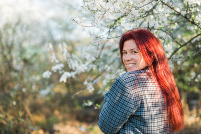 Portrait of young woman standing against trees