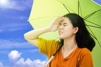 Young woman looking away against sky