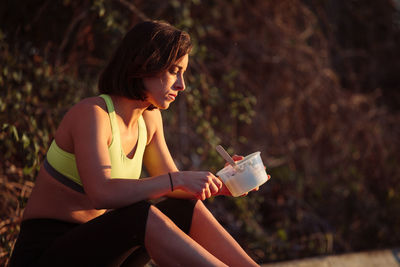 Young woman eating food while sitting at park