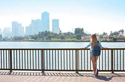 Woman standing on railing against cityscape