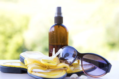 Close-up of flip-flops with sunglasses and perfume sprayer on table