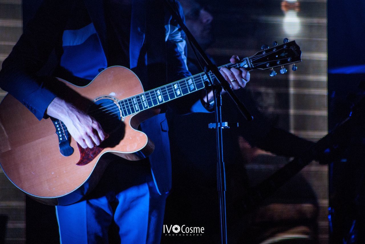 MIDSECTION OF MAN PLAYING GUITAR AT NIGHTCLUB