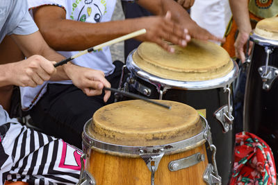 Midsection of people playing drum