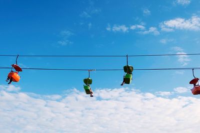 Low angle view of birds on cable against sky